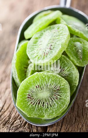 Tranches de kiwi confites ou glaces dans une pelle métallique sur bois (Focus sélectif, Focus au milieu de la première tranche) Banque D'Images