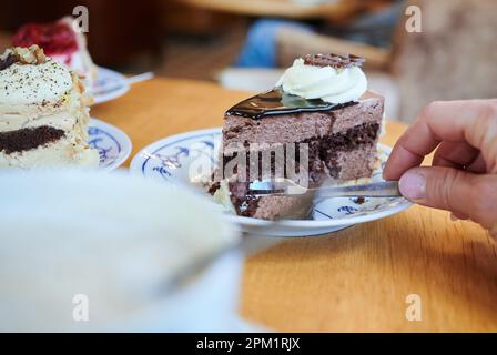 Sellin, Allemagne. 24th mars 2023. Une femme fait un morceau de gâteau avec une fourchette à gâteau, tandis qu'un autre morceau de gâteau est assis sur la table dans un café. Selon leurs propres déclarations, une proportion considérable d'adultes mangent moins de bonbons depuis la crise de Corona. (À l'enquête dpa: 'Un bon quartier mange moins de bonbons depuis Corona') Credit: Annette Riedl/dpa/Alay Live News Banque D'Images