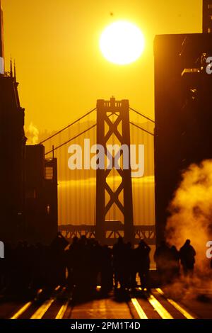 San Francisco, États-Unis. 10th avril 2023. Les gens prennent des photos de l'alignement du lever du soleil avec California Street et Bay Bridge. Le soleil se lève en alignement avec la rue Californie et le pont de la baie à San Francisco de 8 avril à 10 avril et cela se produit deux fois par an. Au cours de ces trois jours, près de mille personnes se rassemblent dans California Street et tirent pour le lever du soleil. Depuis que le soleil se lève alignement avec California Street et Bay Bridge, certains médias et des gens l'ont appelé comme California Henge. Crédit : SOPA Images Limited/Alamy Live News Banque D'Images