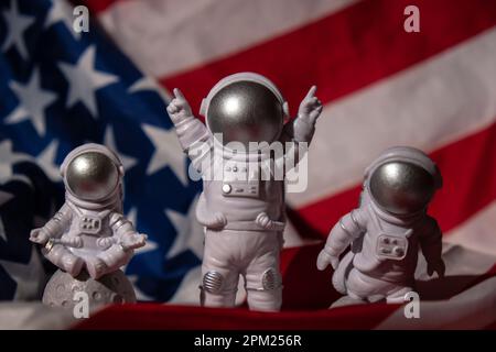 Trois jouets en plastique figurent astronaute sur le drapeau américain arrière-plan espace de copie. 50th anniversaire des États-Unis atterrissage sur la Lune concept de voyage hors terre, vols commerciaux privés de spaceman. Missions spatiales et durabilité Banque D'Images