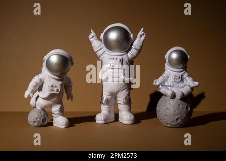 Trois jouets en plastique figurine astronaute sur fond beige espace de copie. Concept de voyage hors terre, vols commerciaux privés de spaceman. Missions spatiales et durabilité Banque D'Images