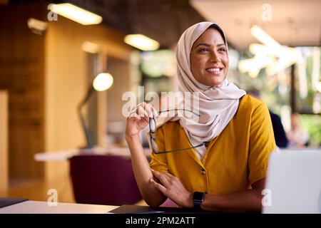 Femme d'affaires mature portant un foulard travaillant sur un ordinateur portable au bureau Banque D'Images