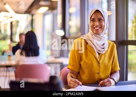 Femme d'affaires mature portant un foulard travailler au bureau écrire au bureau dans un ordinateur portable Banque D'Images