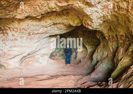 Vue arrière d'un homme à l'intérieur d'une grotte contre une chute d'eau à Sipi Falls, Kapchorwa, Ouganda Banque D'Images