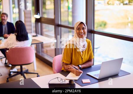 Femme d'affaires mature portant un foulard travailler au bureau écrire au bureau dans un ordinateur portable Banque D'Images