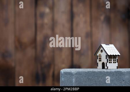 Modèle d'une maison en bois avec espace de copie sur la gauche sur le fond d'un mur en bois. La maison est sur une dalle de béton, le concept de Banque D'Images