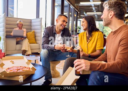 Le personnel de la réunion informelle au bureau avec Takeaway Pizza et boissons Banque D'Images