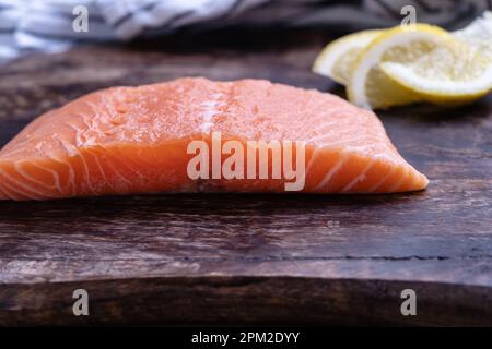 Filet de saumon frais avec tranches de citron sur planche à découper en bois, préparation de la nourriture, ingrédients, gros plan Banque D'Images