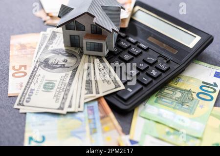 Modèle miniature de maisons sur des billets en euros empilés, sur fond blanc isolé. Concept d'investissement immobilier. Économiser de l'argent pour la retraite future. Banque D'Images