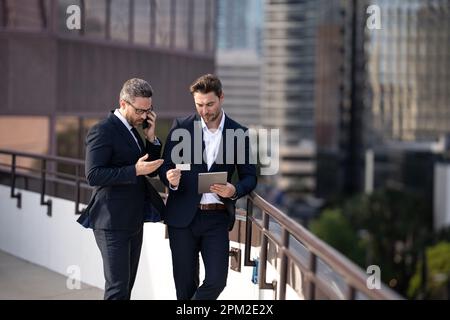 Homme d'affaires à Ney York. Les hommes d'affaires font équipe avec une tablette pour ordinateur portable à l'extérieur. Les hommes d'affaires recherchent une tablette avec succès dans la ville. Banque D'Images