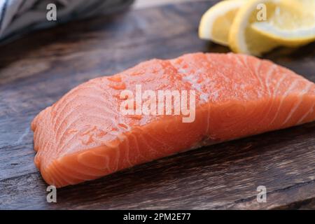 Filet de saumon frais avec tranches de citron sur planche à découper en bois, préparation de la nourriture, ingrédients, gros plan Banque D'Images