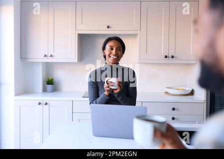 Couple à la maison travaillant sur un ordinateur portable sur le comptoir dans la cuisine Banque D'Images