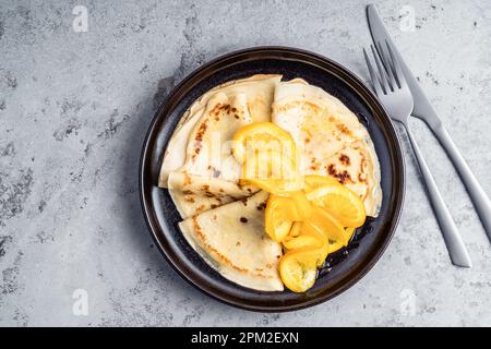 Plaque de crêpes orange sur fond gris, directement au-dessus. Crêpes Suzette Banque D'Images