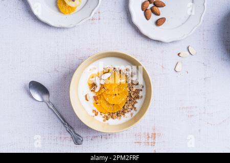 Bols de céréales au yaourt avec fruits orange sur bois blanc, vue du dessus. Repas végétarien sain pour le petit déjeuner Banque D'Images