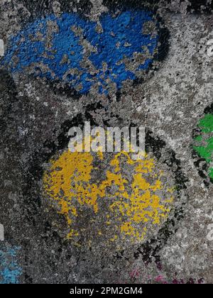 Une ancienne fresque de graffiti aux couleurs jaune et vert orne un trottoir Banque D'Images