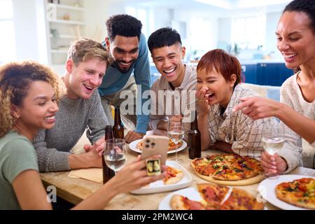 Des amis qui prennent Selfie au téléphone s'amuser à la maison dans la cuisine manger des pizzas faites maison Banque D'Images
