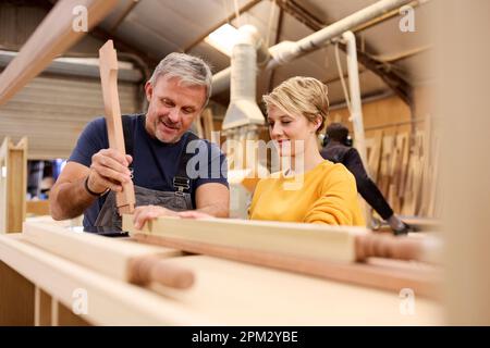 Apprentissage féminin compétences d'apprentissage de menuisier d'âge mûr masculin dans l'atelier de meubles Banque D'Images