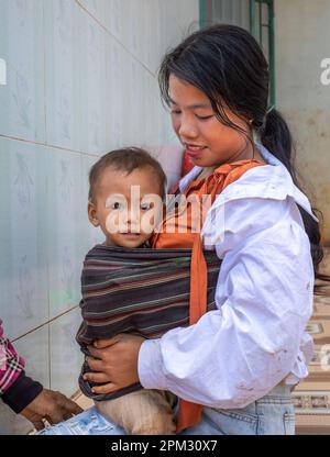 Une jeune mère de la minorité ethnique de Jerai tient son jeune enfant sur ses genoux dans les Highlands centraux du Vietnam. Banque D'Images