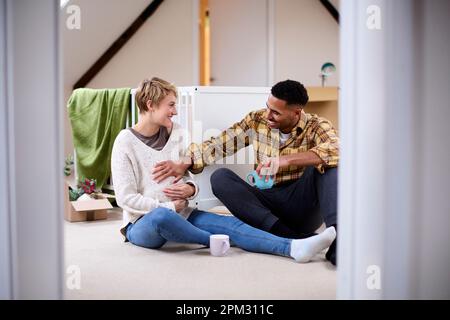 Couple s'attendant à bébé se détendre dans la pépinière de la nouvelle maison avec déplacer dans des boîtes Banque D'Images