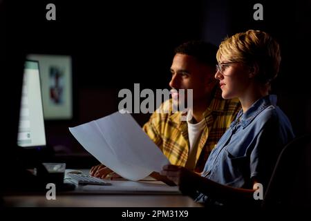 Deux collègues d'affaires aux bureaux du bureau travaillent en retard sur le projet ensemble Banque D'Images