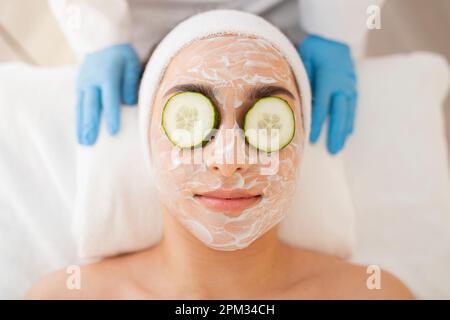 Soins de la peau. Belle femme avec masque de collagène et tranches de concombre sur les yeux Banque D'Images