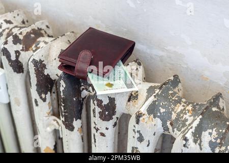 Un radiateur de sorge dans une vieille maison et un portefeuille avec un billet de banque de 100 zloty, Polka argent, concept, augmentation des prix de l'énergie et du chauffage, Un problème pour t Banque D'Images