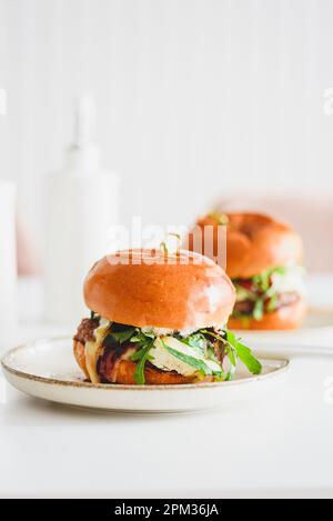 Deux délicieux hamburgers faits maison avec du bœuf, du fromage et des légumes sur une table en bois blanc Banque D'Images