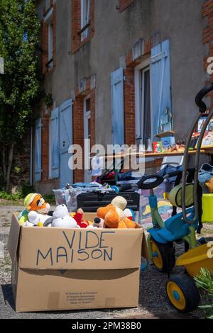 Un plan vertical de vente de garage avec de nombreux jouets en face d'une vieille maison Banque D'Images
