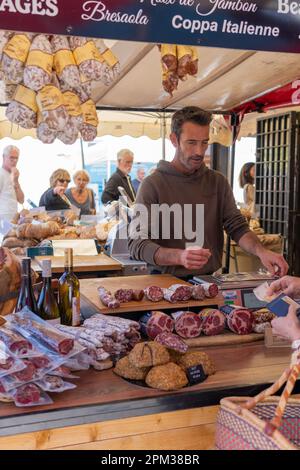 Un cliché vertical de vendeur sur le marché local avec un choix varié de vins de jambon sec et de produits faits maison Banque D'Images
