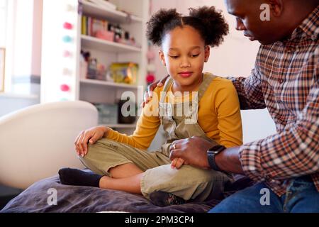 Père réconfortant fille triste assis sur le lit à la maison Banque D'Images