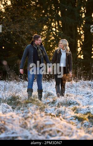Couple aimant tenant la main sur Snowy Walk dans la campagne d'hiver Banque D'Images