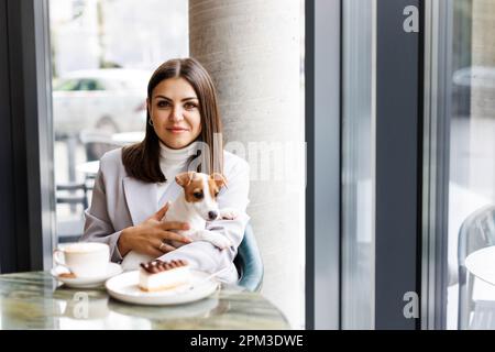 Femme caucasienne et Jack russell terrier regarder le gâteau avec une bougie. Le chien et le propriétaire célèbrent l'anniversaire Banque D'Images