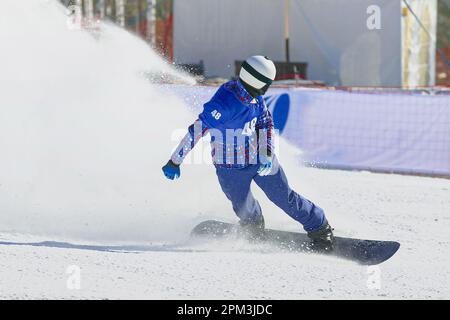 les snowboardeurs mâles arrêtent le snowboard après la compétition de fin de course, des éclaboussures de neige sous le bord Banque D'Images