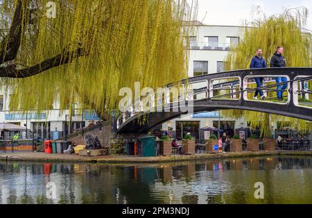 Camden Town, Londres, Royaume-Uni : deux personnes sur une passerelle traversant le canal Regents près du marché Camden avec des saules. Banque D'Images