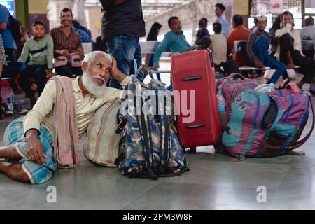 Un homme musulman âgé, barbu, se détendant à côté de ses bagages en attendant un train à Chhatrapati Shivaji Maharaj Terminus à Mumbai, en Inde Banque D'Images