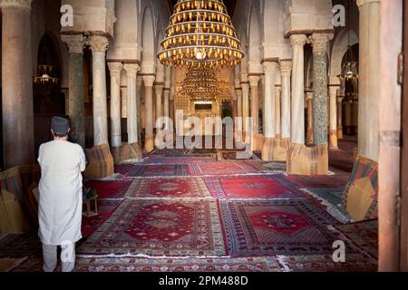 Sousse, Tunisie, 15 janvier 2023 : intérieur de la Grande Mosquée de Sousse avec lustres et tapis de prière avec un dévot musulman à côté Banque D'Images