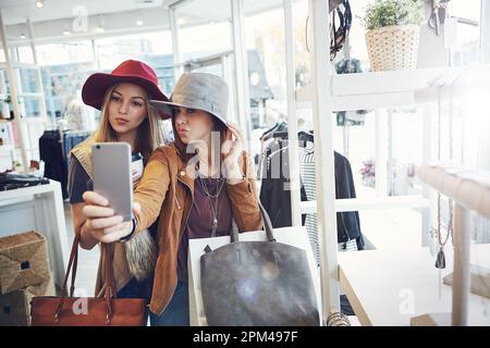 Faites vos courses jusqu'à la prochaine selfie... ou jusqu'au prochain selfie. deux jeunes amies prenant des selfies lors d'une séance de shopping. Banque D'Images