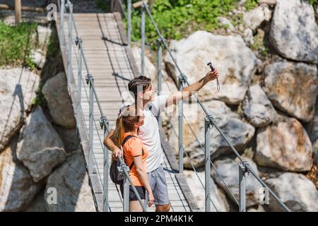 Deux jeunes randonneurs, une femme et un homme qui profitent d'un paysage naturel magnifique, prenant des photos de selfie d'une cascade de rivière de montagne Banque D'Images