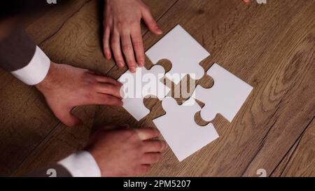 Groupe de gens d'affaires qui mettent un puzzle sur une table Banque D'Images