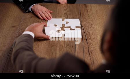 Groupe de gens d'affaires qui mettent un puzzle sur une table Banque D'Images