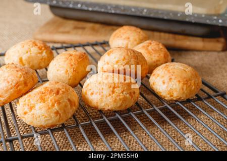 Des boules de pain au fromage brésilien traditionnel fraîchement cuites se trouvent sur la grille de refroidissement de la table de cuisine Banque D'Images