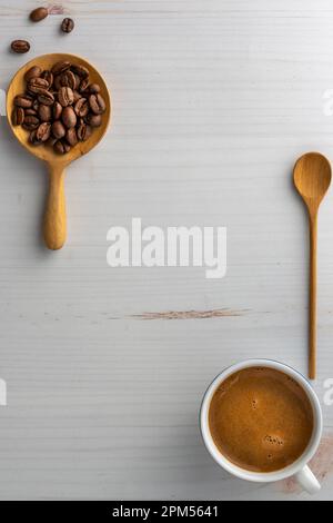 Grains de café dans une cuillère en bois et une tasse de café. Ci-dessus. Banque D'Images