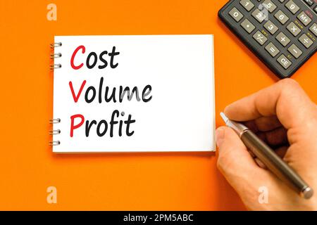 Symbole de profit de volume de coût CVP. Concept mots CVP coût volume profit sur note blanche sur fond orange magnifique. Main d'homme d'affaires. Calculatrice. Buline Banque D'Images