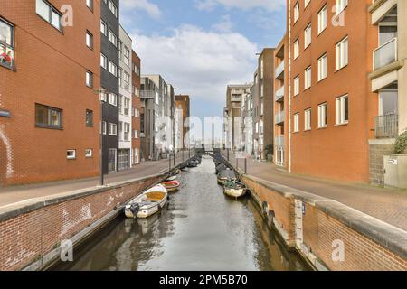 quelques bateaux dans l'eau et des bâtiments de chaque côté du canal qui sont rouge vif avec des fenêtres blanches Banque D'Images