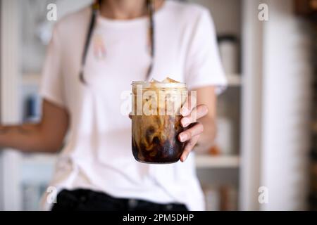 Femme native avec des tresses tenant un pot en verre de café glacé Banque D'Images