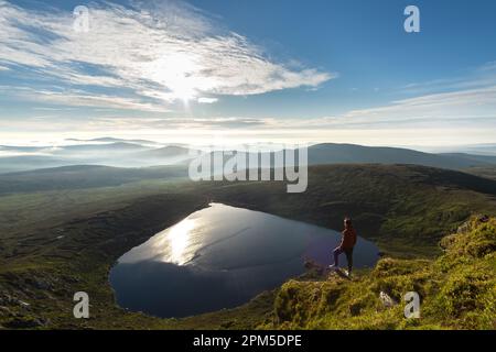 homme regardant du sommet de la montagne au lac en forme de coeur Banque D'Images