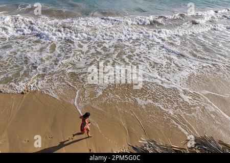 vue en hauteur d'une femme qui court sur la plage avec des vagues Banque D'Images