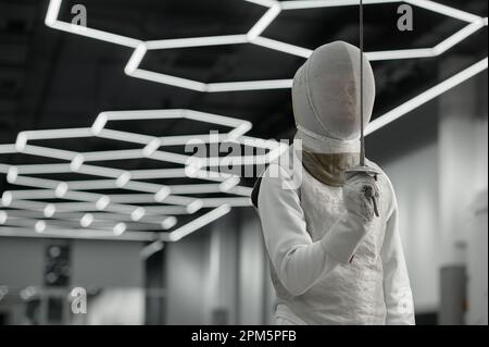 Portrait d'athlète sportif par épée portant des vêtements de protection et un casque lors de l'entraînement Banque D'Images