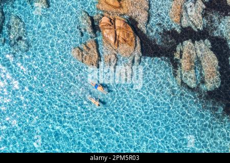 Vue aérienne de l'homme et de la femme nageant dans la mer bleue, plage rocheuse Banque D'Images
