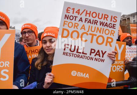 Londres, Royaume-Uni. 11th avril 2023. Un manifestant tient un écriteau qui indique « £14 par heure n'est pas un salaire équitable pour un médecin junior » pendant la démonstration. Des milliers de médecins subalternes ont organisé une manifestation à Trafalgar Square alors qu'ils commenceraient leur grève de quatre jours pour réclamer le rétablissement de la pleine rémunération. Crédit : SOPA Images Limited/Alamy Live News Banque D'Images